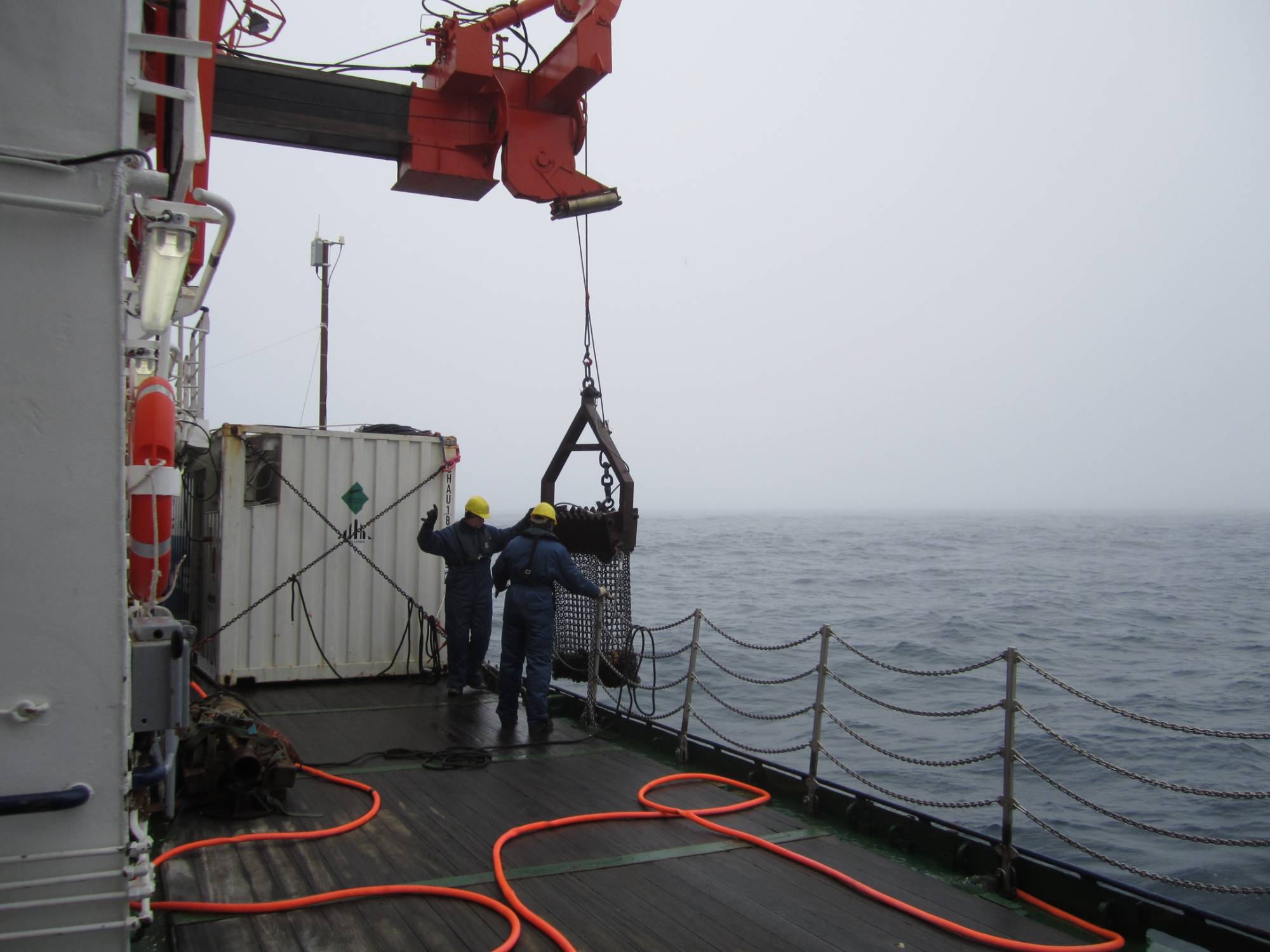 Two people with a pulley system being used to lift material out of ocean