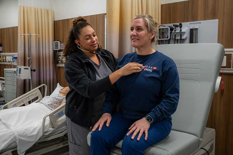 One nursing student checking heart beat of another